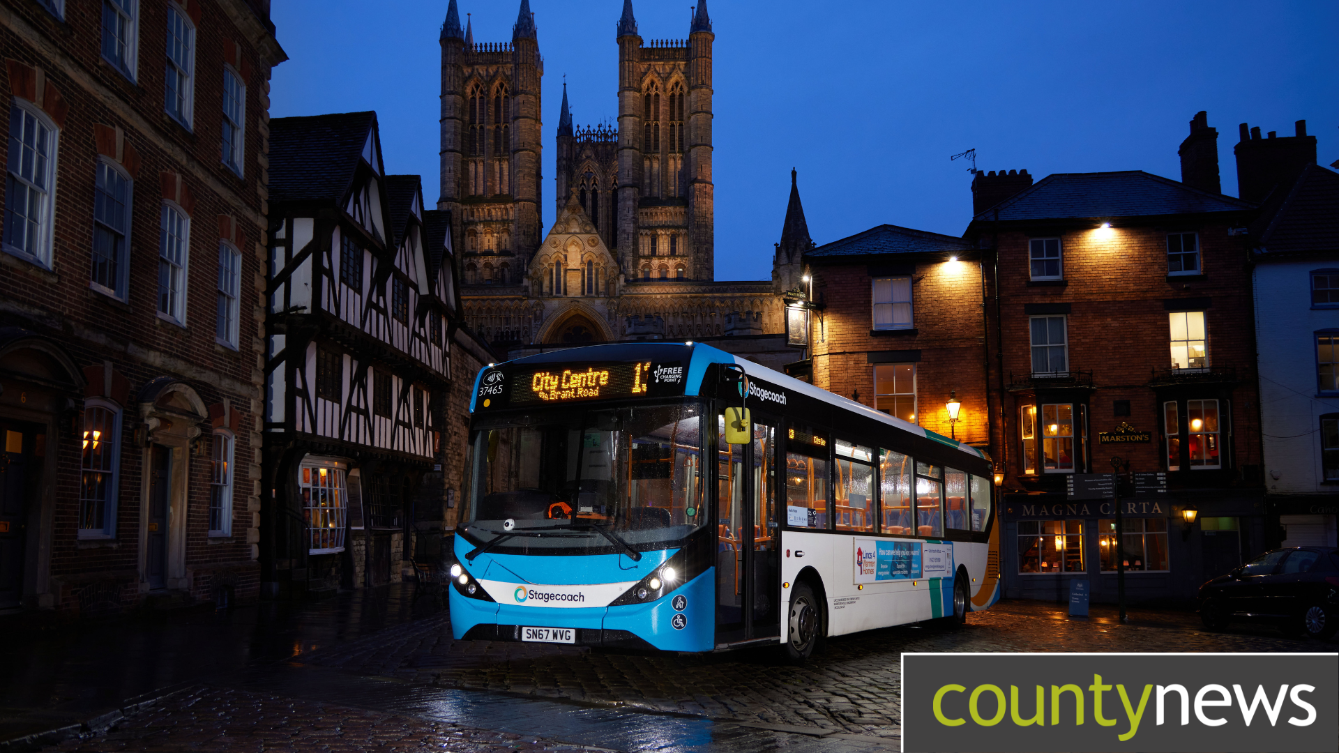 A bus at night with Lincoln Cathedral behind