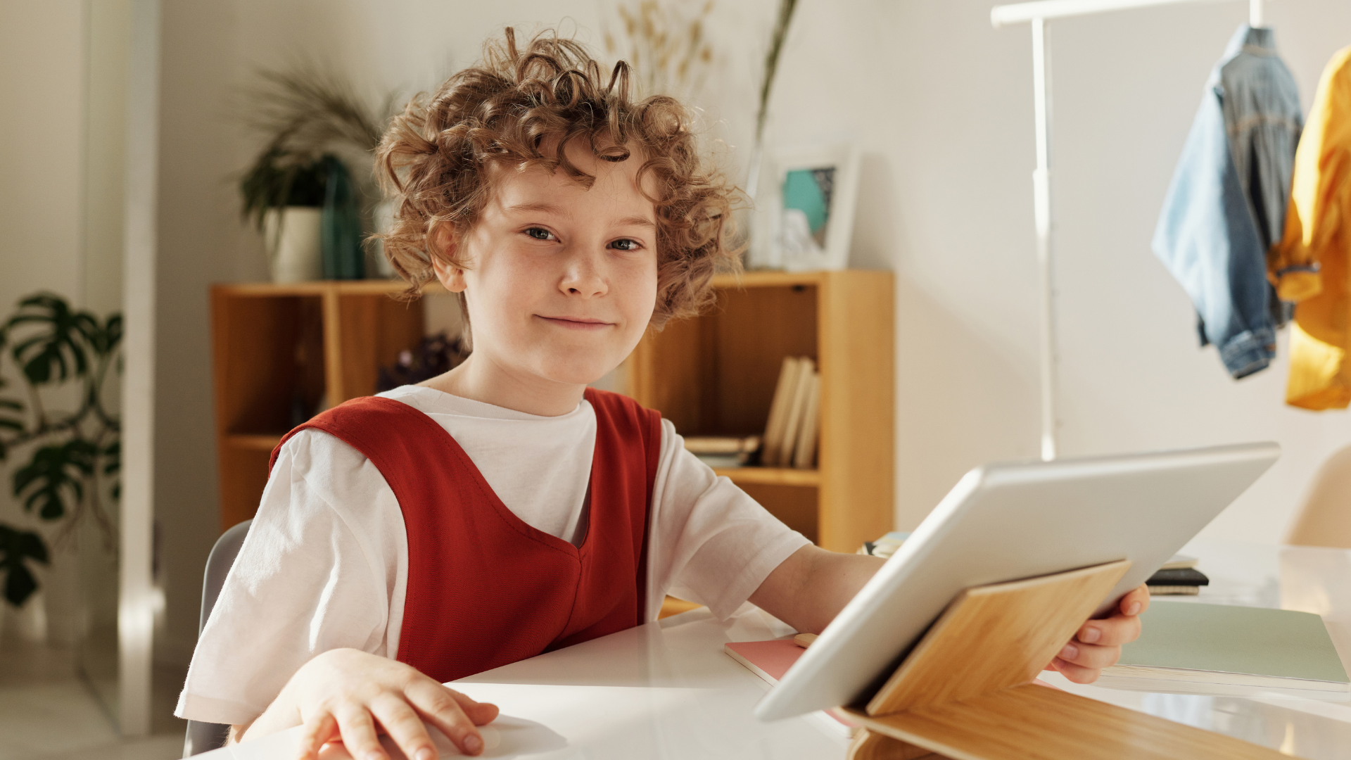 A child sat at a table looking at an iPad