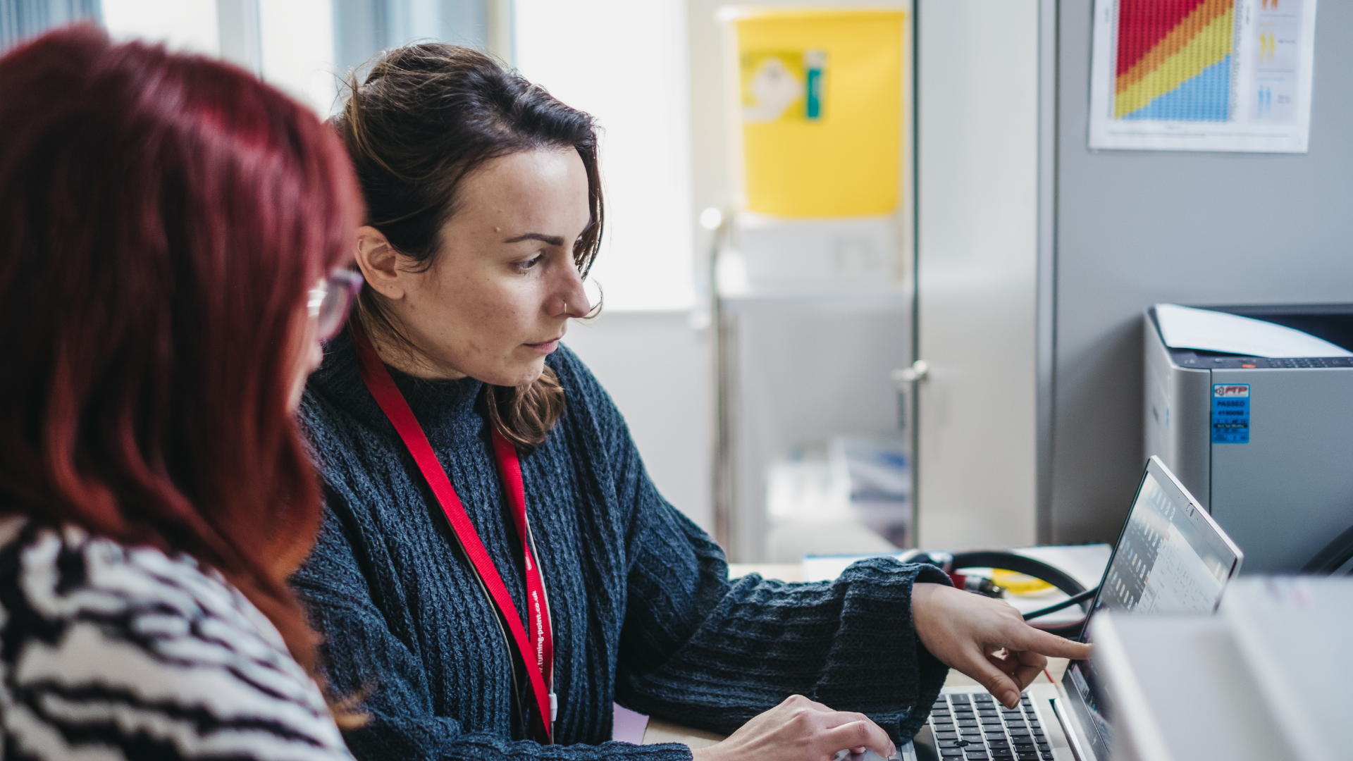 Two ladies sit together looking at a computer screen