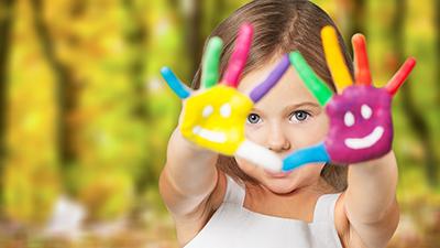 Image of a child looking through their painted hands