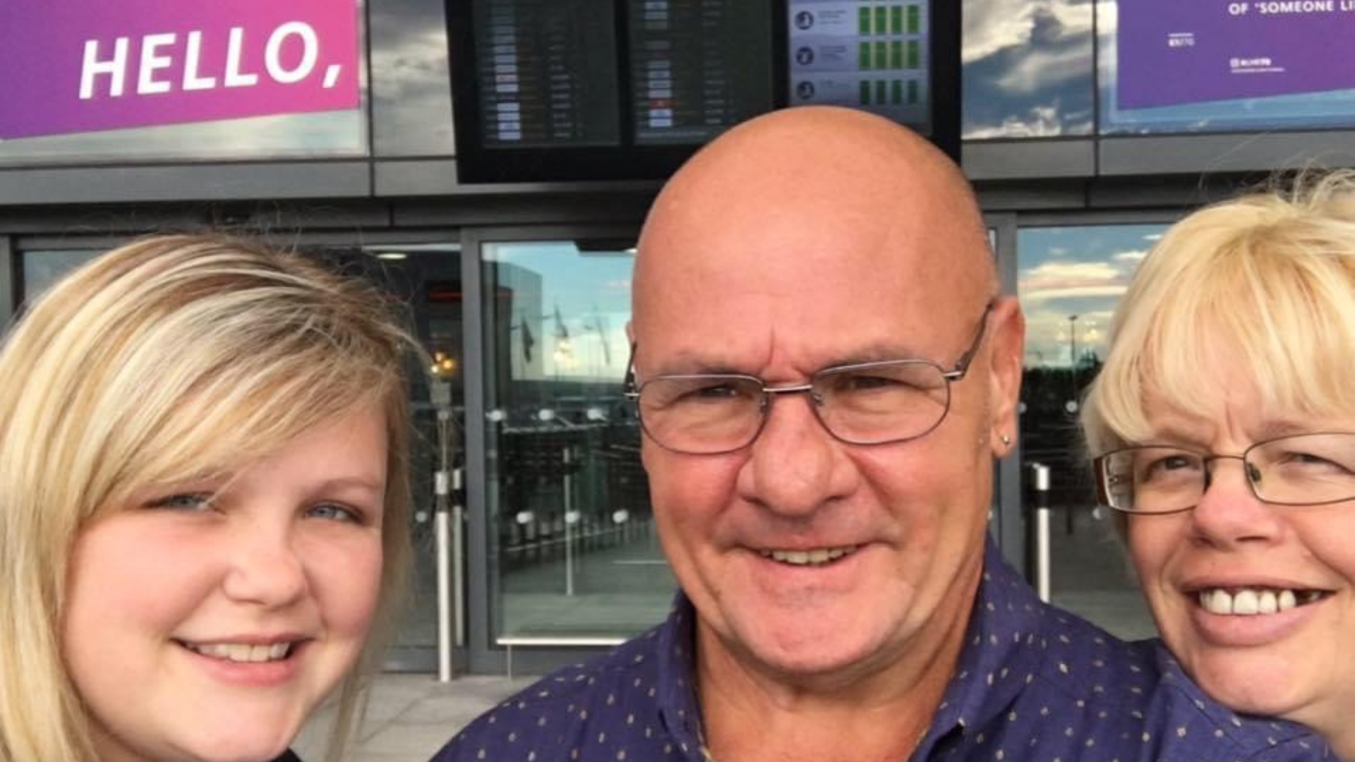 A young woman with blonde hair smiling at the camera, next to a man with a bald head and glasses, stood in the middle and to the right a middle aged woman wearing glasses smiling a the camera.