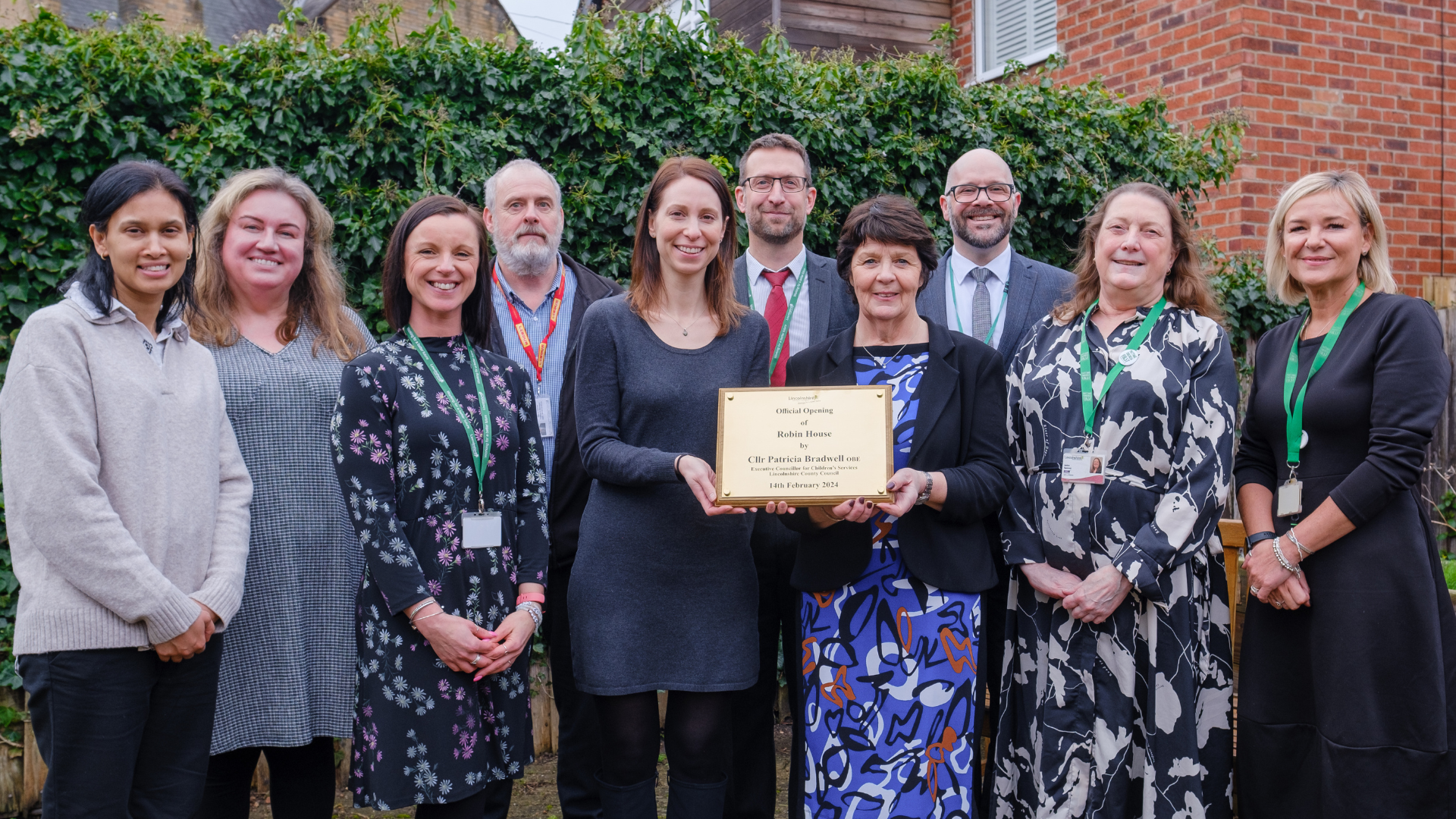 Professional stood in a line with Councillor Bradwell presenting a brass plaque