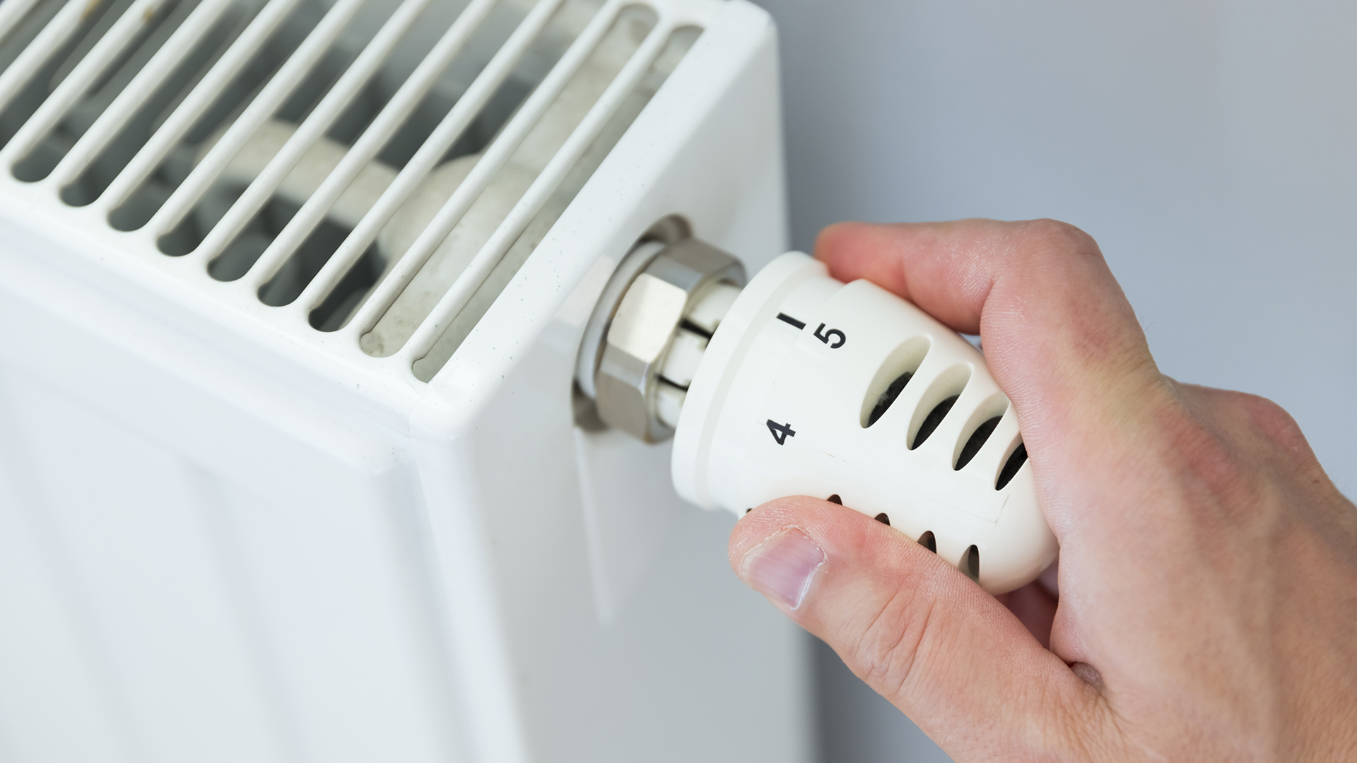 A person turning down the temperature on a radiator